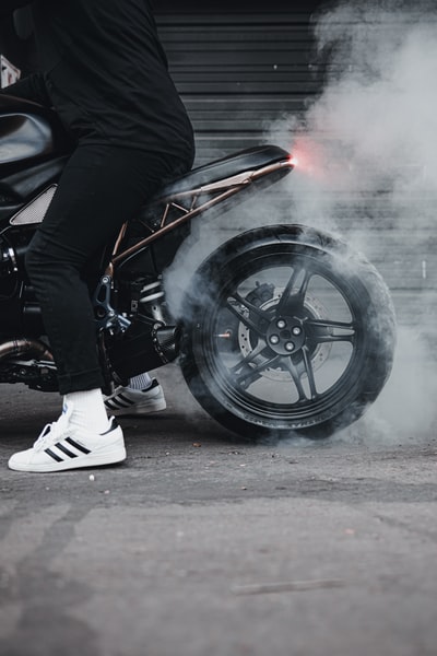 穿着黑色夹克和白色裤子的男子骑着黑色摩托车